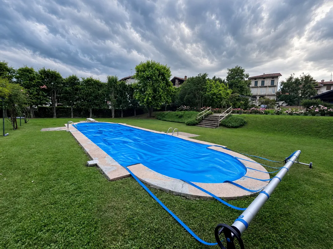 In-ground pool with a summer bubble cover and a wheeled roller at the poolside