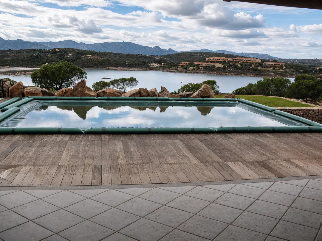 Green winter cover with water tubes on a rectangular pool looking out over water and mountains