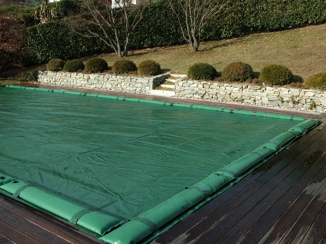 Green winter cover with water tubes on a residential pool