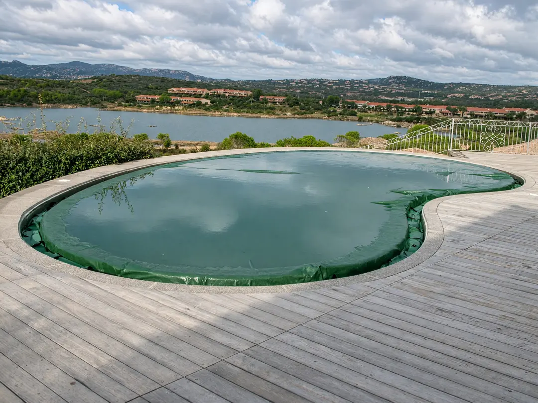 Green winter cover on a kidney-shaped pool looking out over the hills